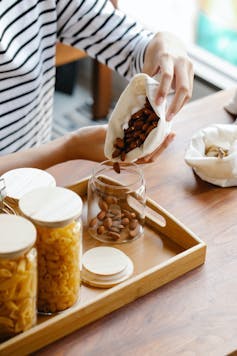 Une femme transvase des produits achetés en vrac dans des bocaux vierges