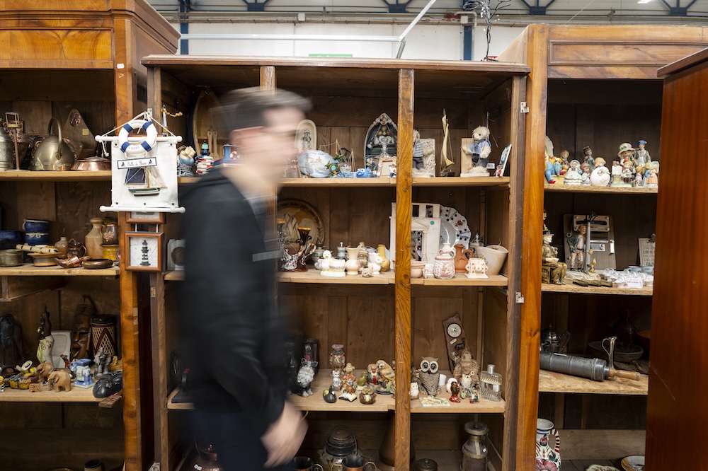Homme flou passant devant une étagère remplie d’objets anciens dans un magasin vintage
