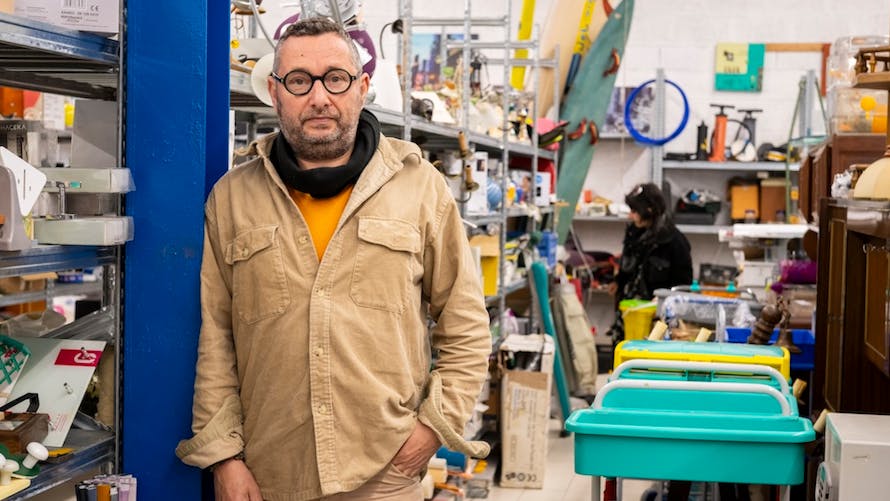 Homme debout dans un magasin de seconde main entouré d'étagères remplies d'objets divers