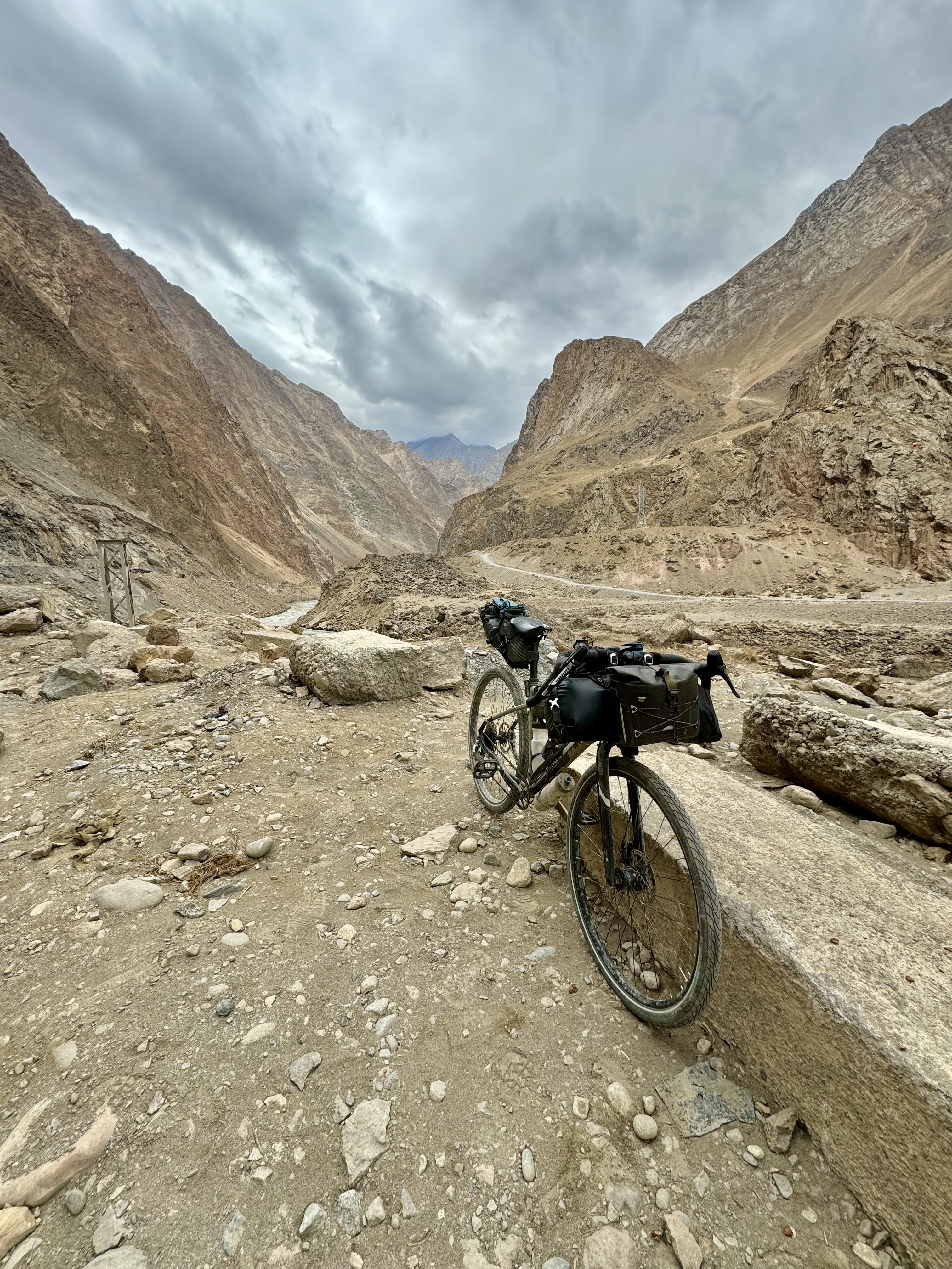 Vélo de randonnée chargé sur un sentier rocailleux dans une vallée montagneuse désertique