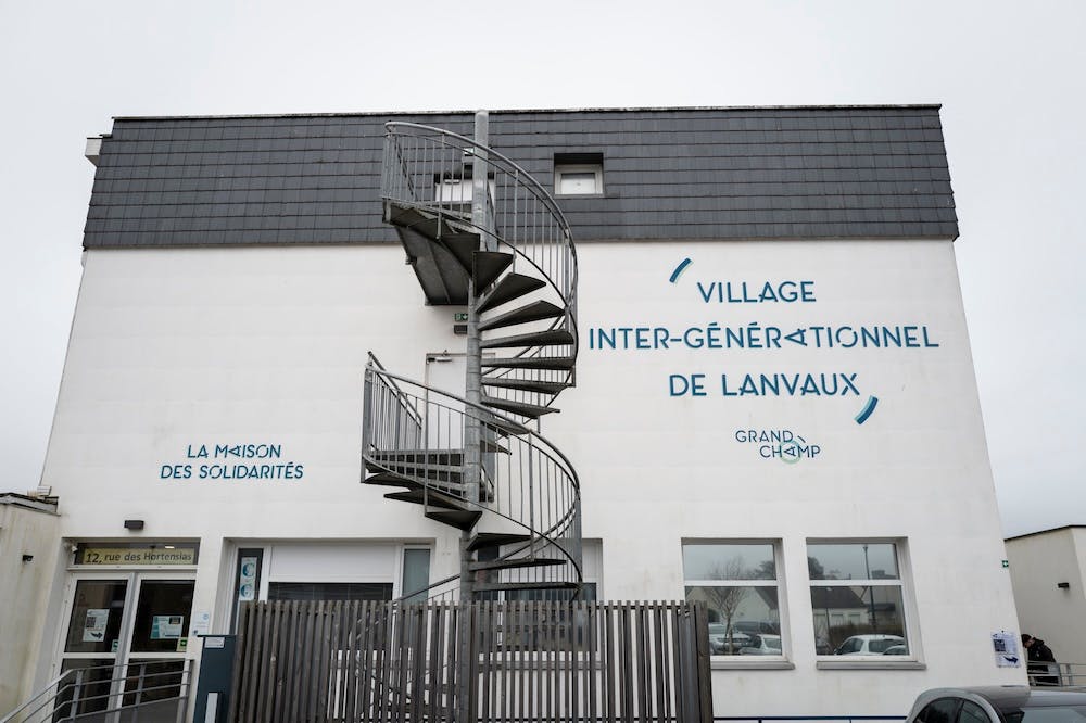 Escalier en colimaçon devant le Village intergénérationnel de Lanvaux, bâtiment blanc à trois étages.