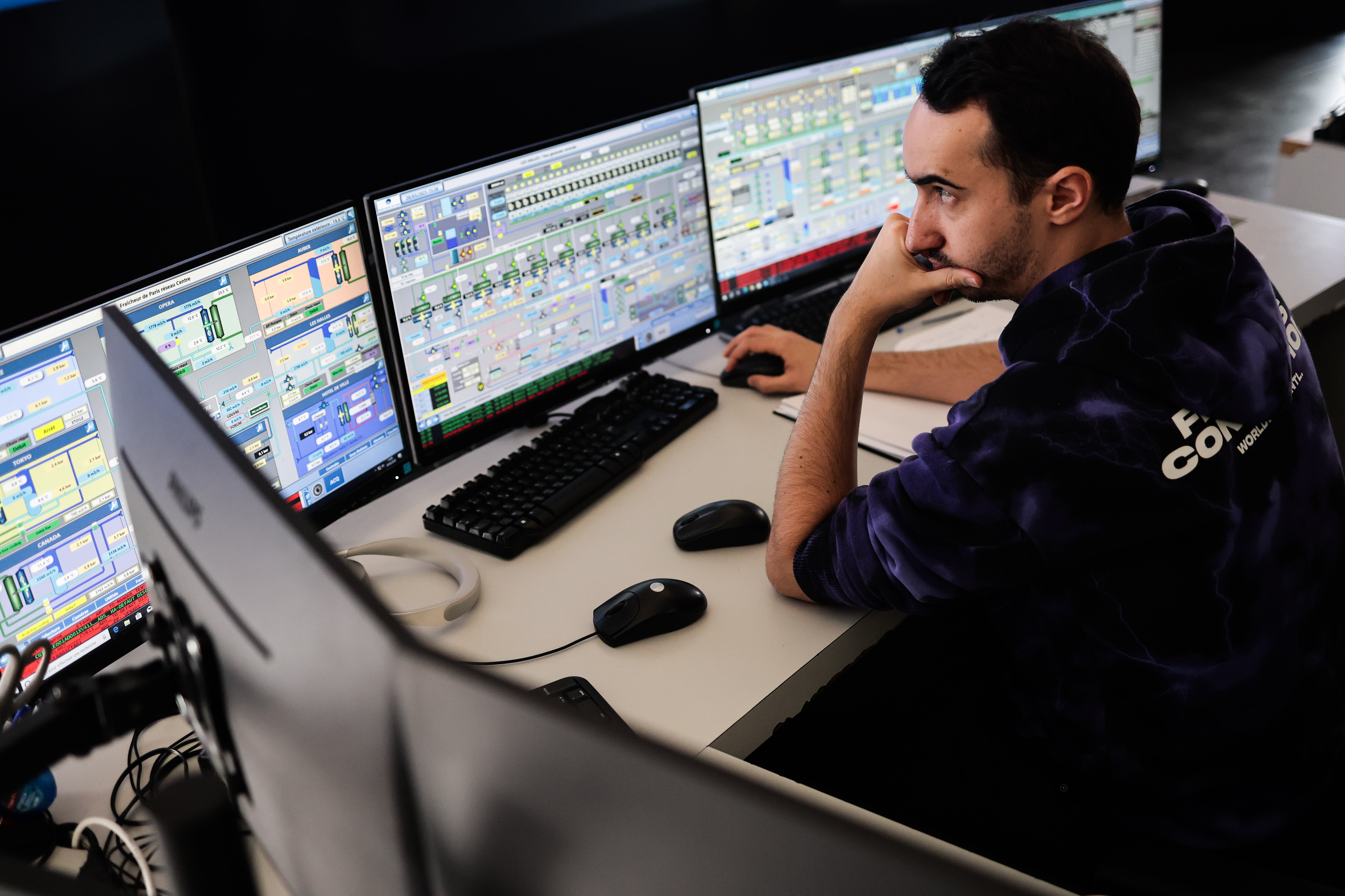Homme travaillant sur plusieurs écrans d’ordinateur affichant des données techniques et des graphiques.