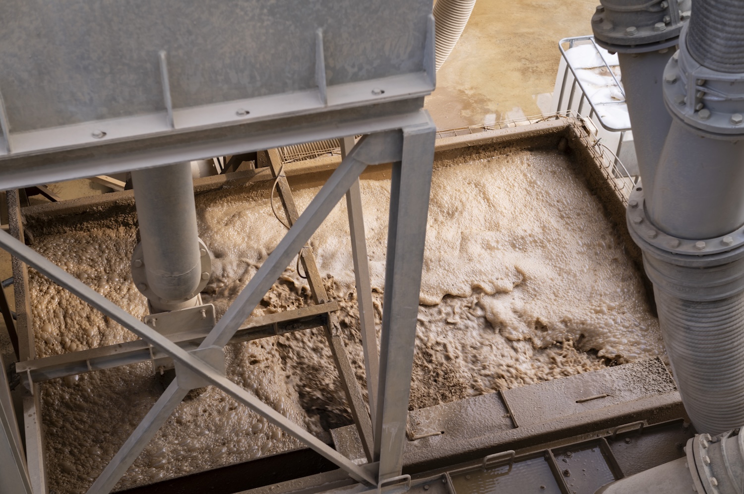 Traitement industriel de boues dans une station d'épuration avec structures métalliques et tuyauteries visibles