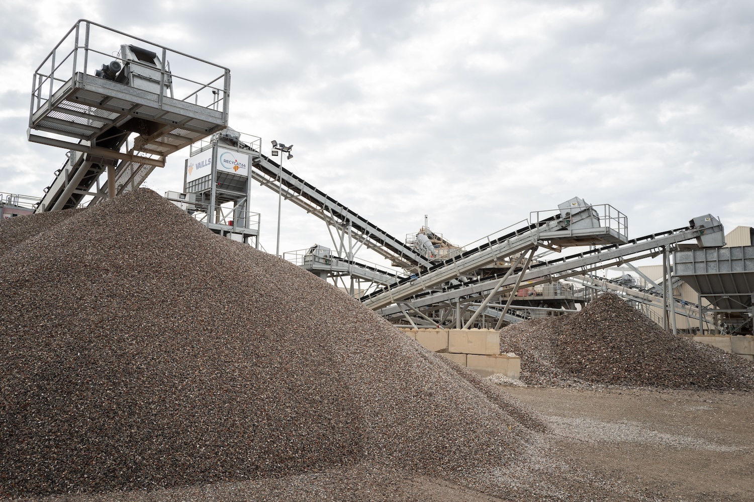 Tas de gravier et convoyeurs dans une carrière sous un ciel nuageux