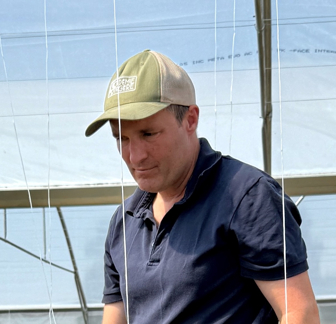 Baptiste Saulnier travaillant dans une serre avec des fils suspendus autour de lui