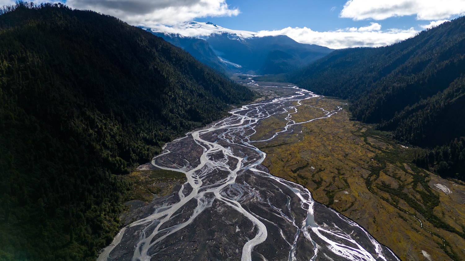Vue aérienne d&#039;une rivière en tresses serpentant entre deux chaînes de montagnes verdoyantes. C&#039;est la vallée glaciaire Michinmahuida. 