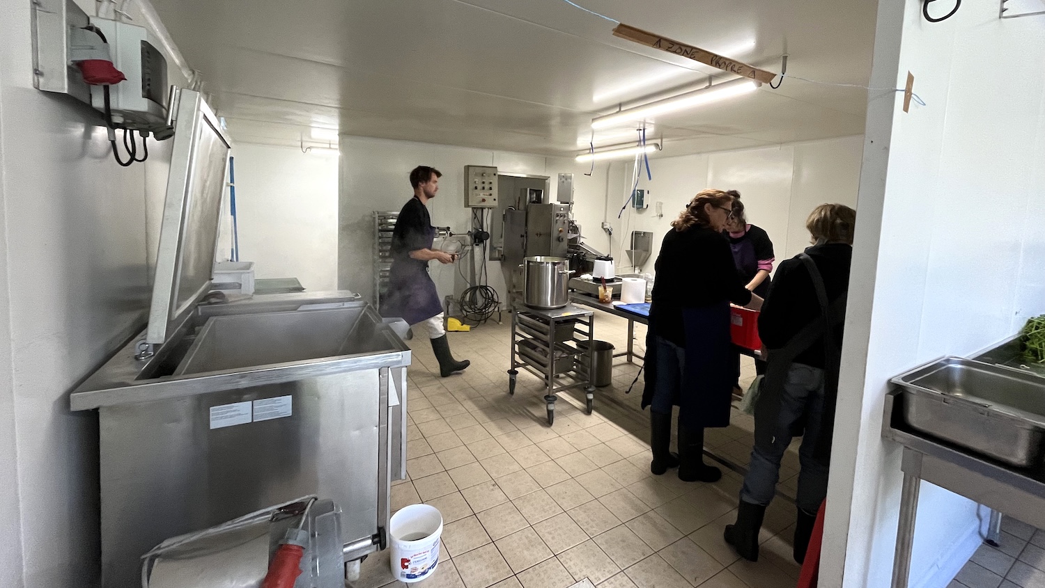 Personnes travaillant dans une cuisine professionnelle équipée de machines et plans de travail en inox.