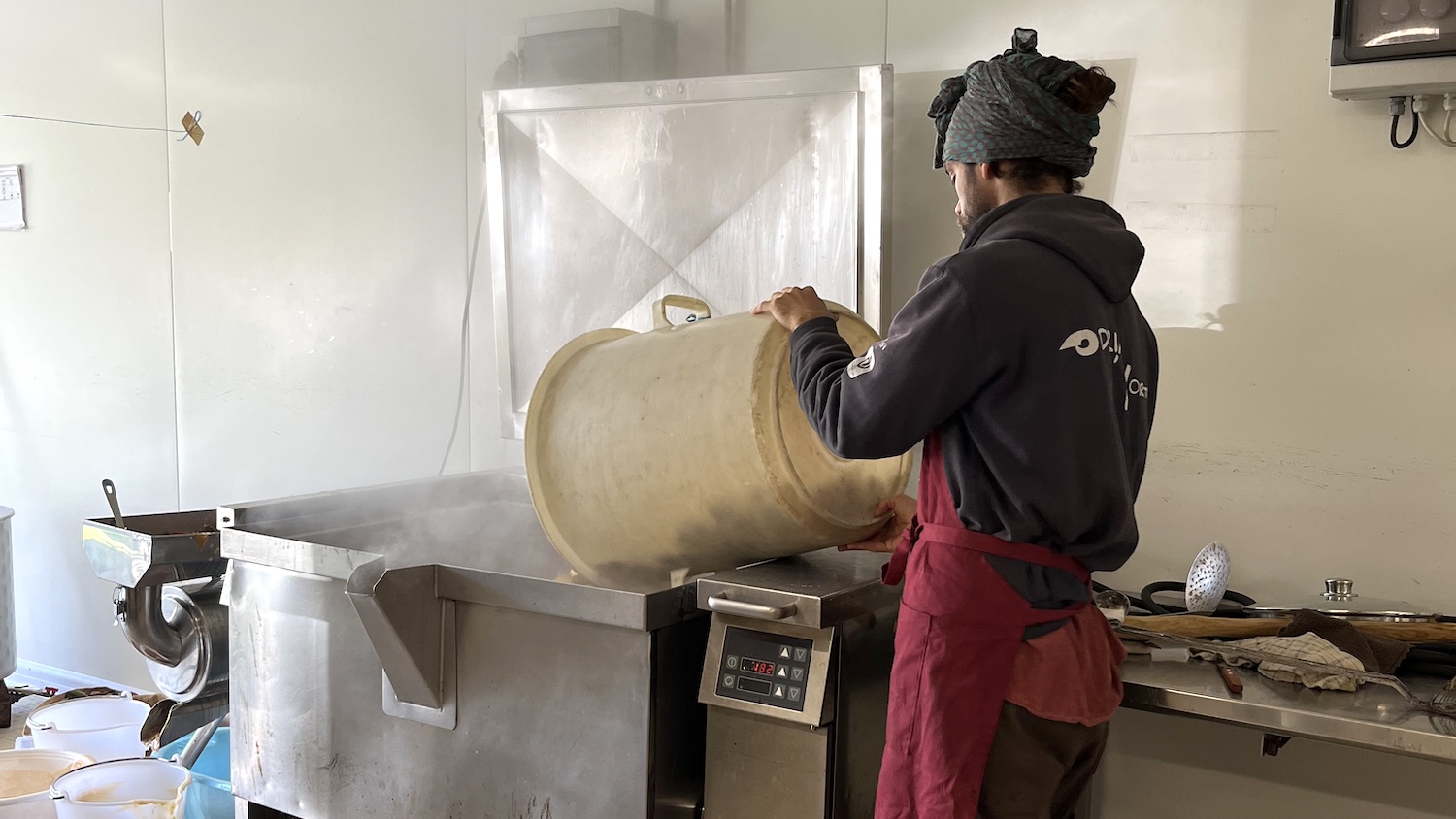 Homme versant des légumes dans une marmite professionnelle pour faire des potages