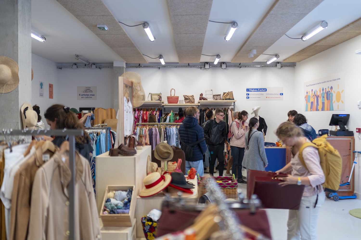 Des personnes font leurs achats dans une friperie bien éclairée et colorée.