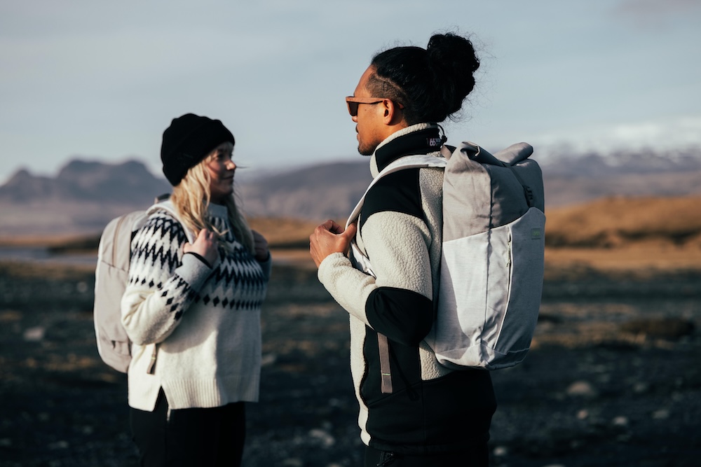 Deux randonneurs en pull chaud et sac à dos Osprey se font face dans un paysage montagneux en arrière-plan