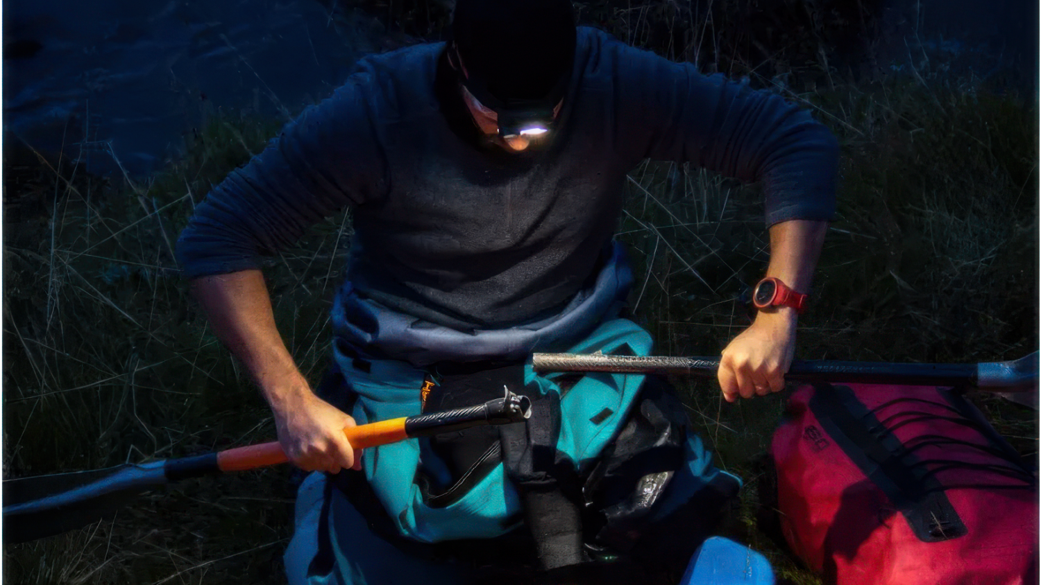 Personne préparant du matériel de kayak au crépuscule avec une lampe frontale Stoots allumée.
