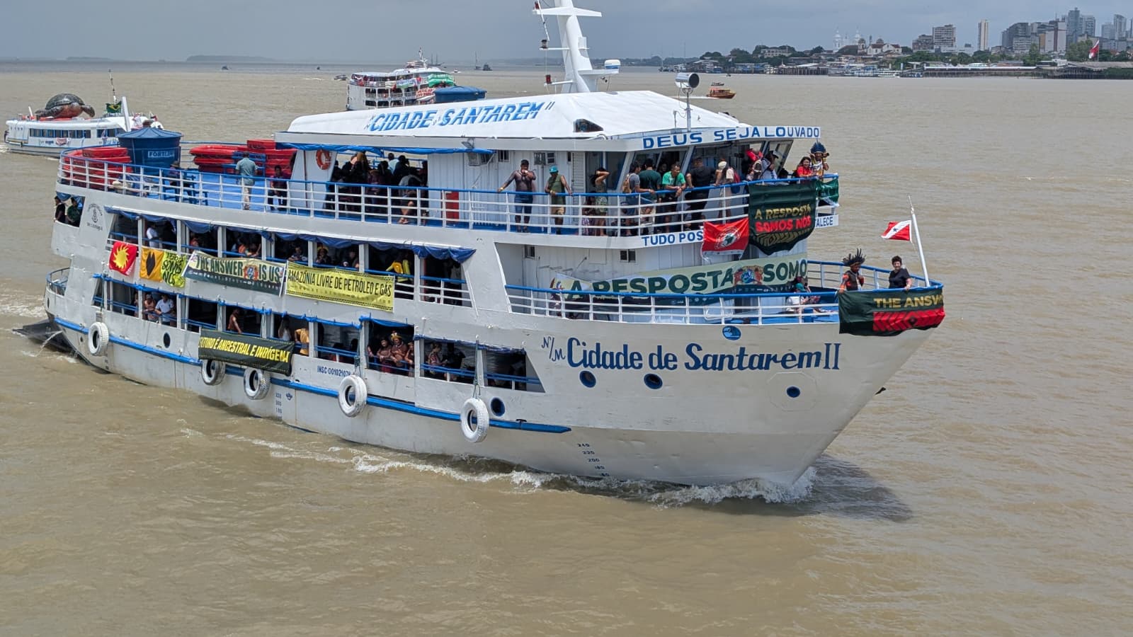 Bateau de passagers naviguant sur un fleuve avec des personnes à bord et des banderoles colorées