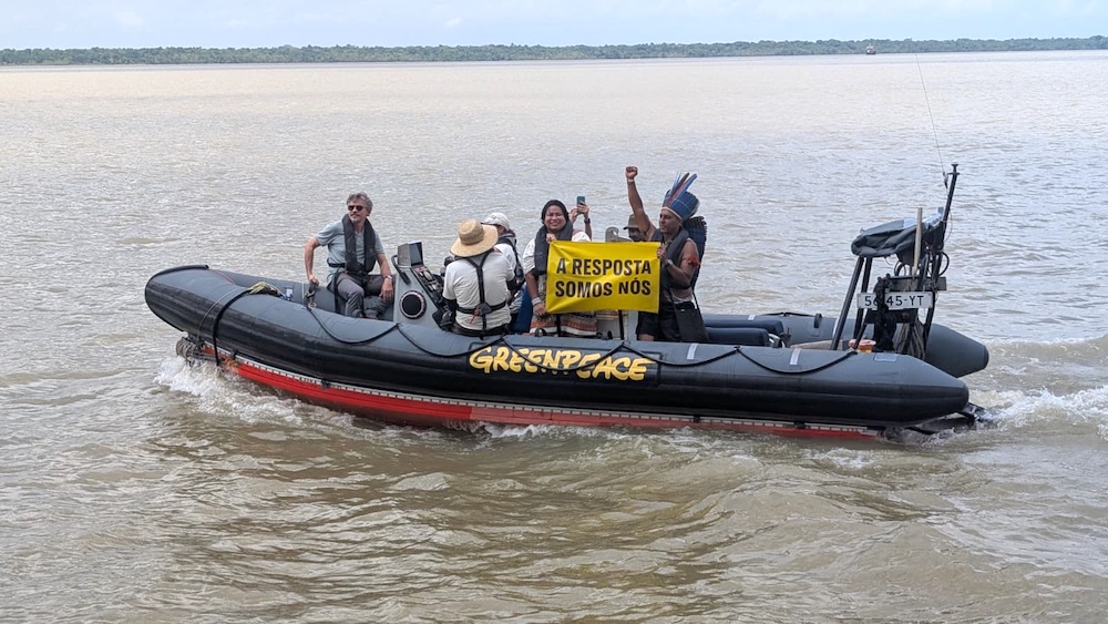 Militants de Greenpeace sur un bateau brandissant une pancarte contre l'exploitation pétrolière.