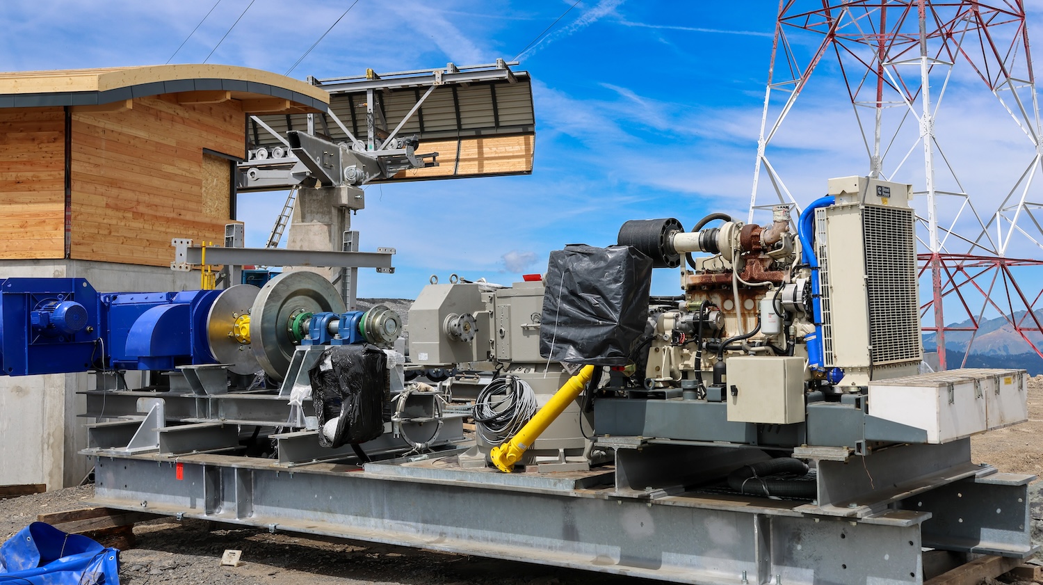 Moteur de remontée mécanique installé en extérieur près d’un bâtiment en bois et pylônes électriques