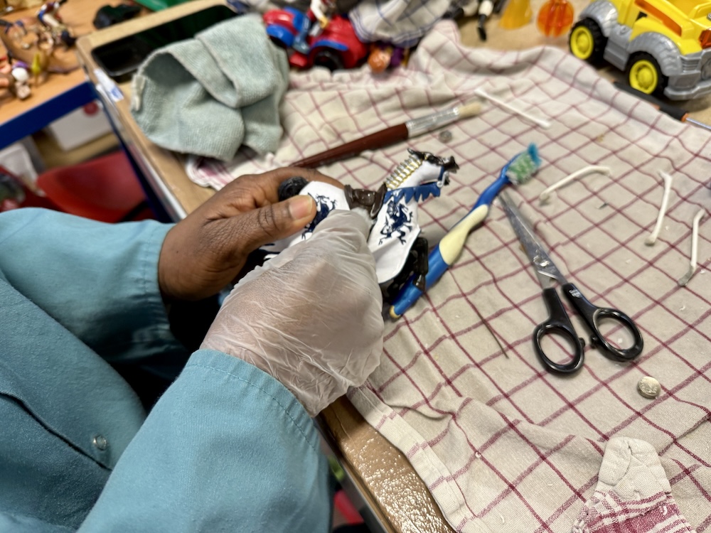 Personne nettoyant un objet avec une brosse à dents sur un plan de travail couvert.