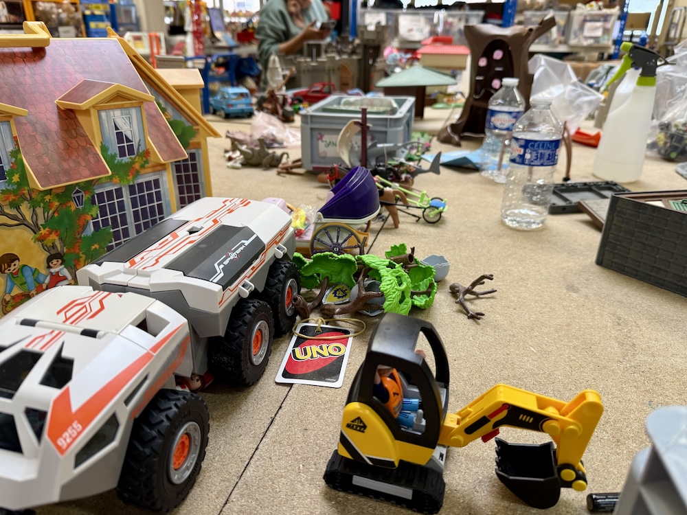 Jouets variés sur une table, incluant camions, maison miniature et carte Uno.