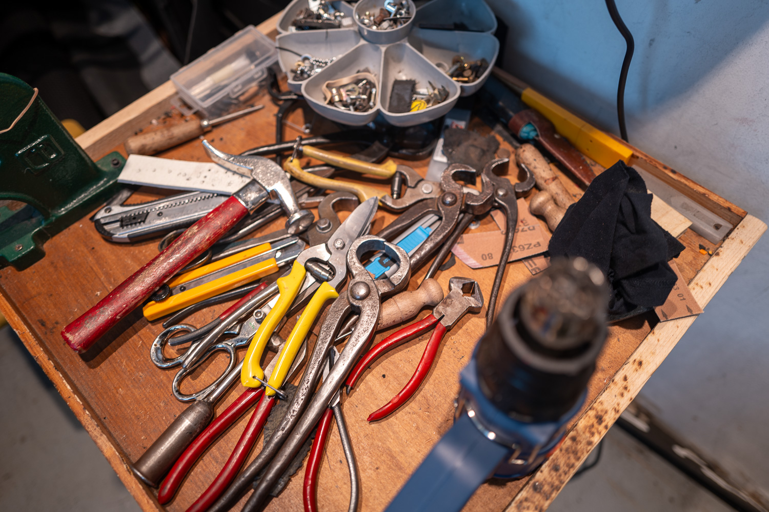 Établi encombré avec pinces, tournevis, vis et divers outils de bricolage.