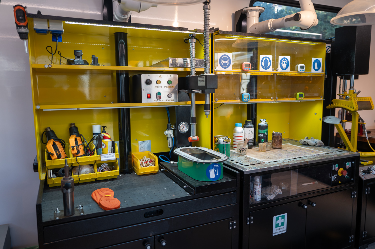 Poste de travail d'atelier avec outils, équipements de sécurité et produits chimiques organisés sur des étagères