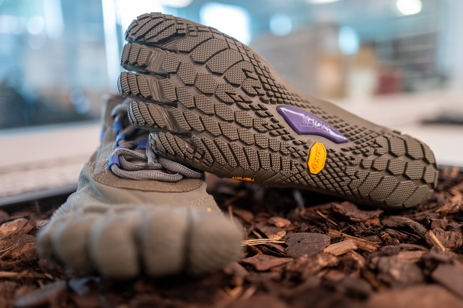 Chaussures minimalistes à orteils séparés posées sur des copeaux de bois.