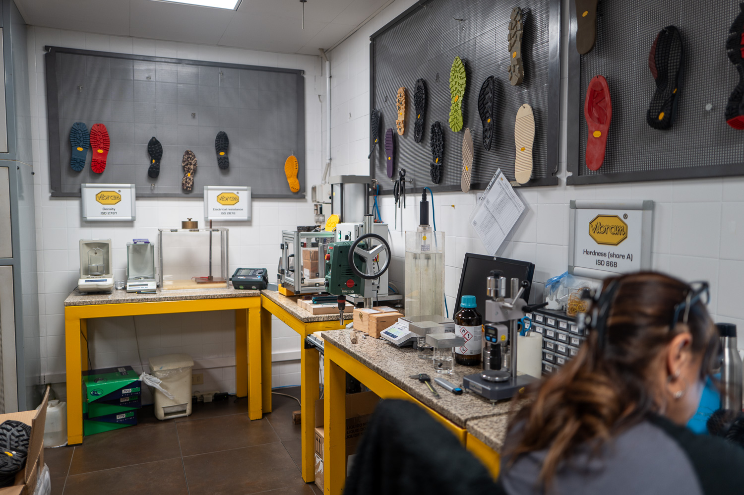 Atelier de fabrication de semelles avec outils, échantillons accrochés au mur et personne au travail