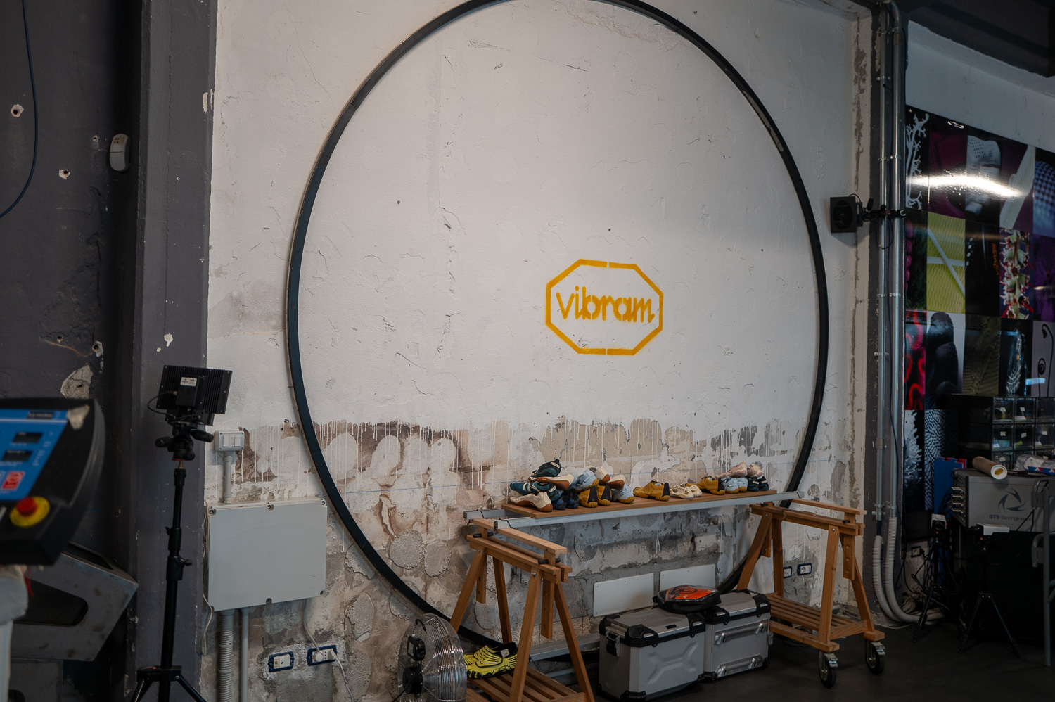 Mur avec un cercle noir, outils posés sur des établis et logo Vibrations au centre.