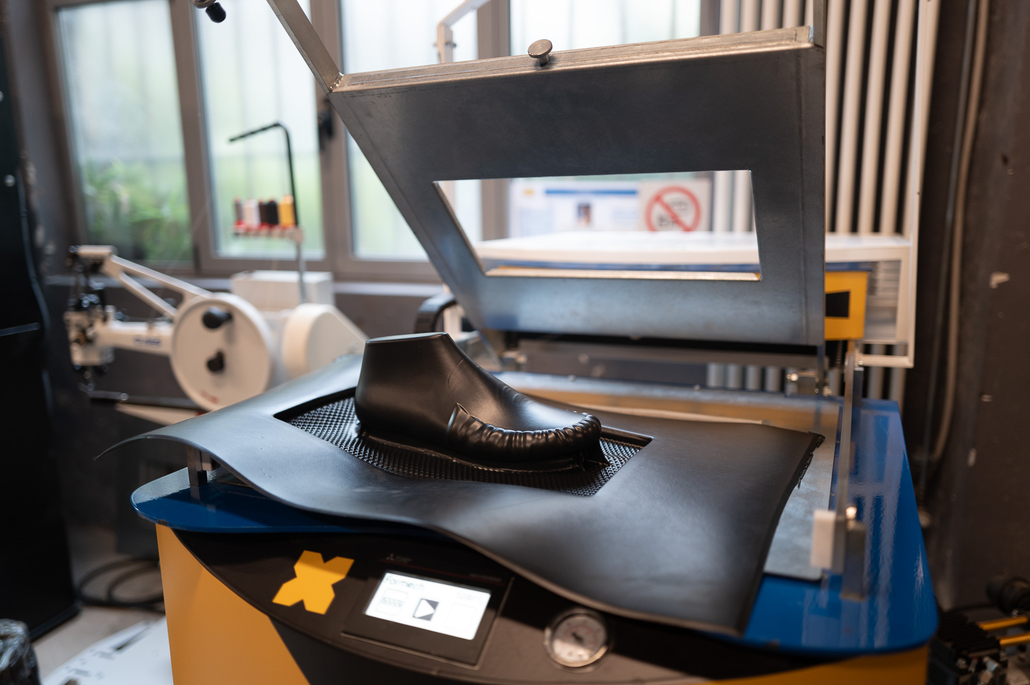 Machine de fabrication de chaussure avec une forme en cuir noir en cours de moulage.