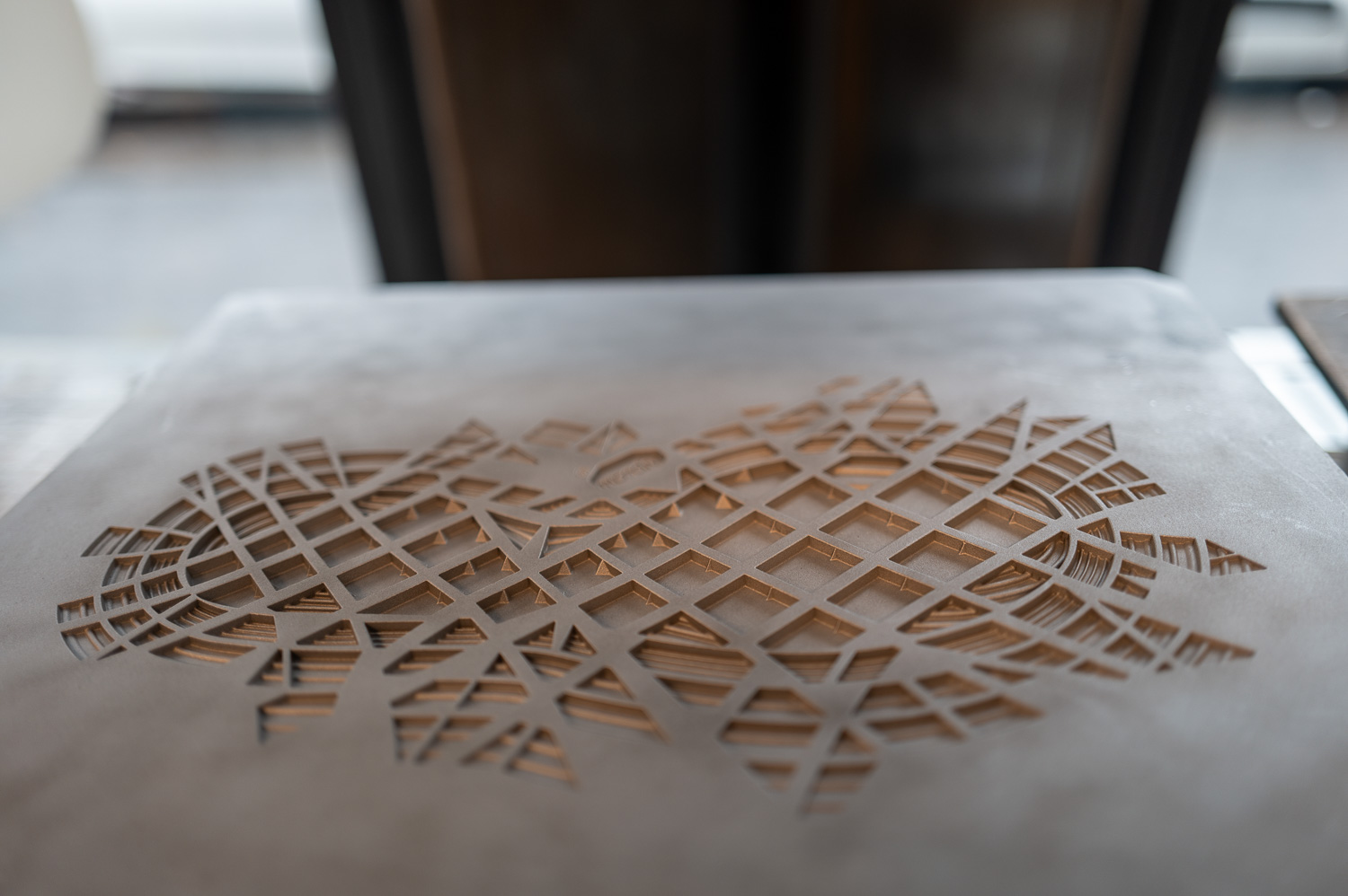 Motif géométrique découpé dans une surface en marbre avec un fond flouté.