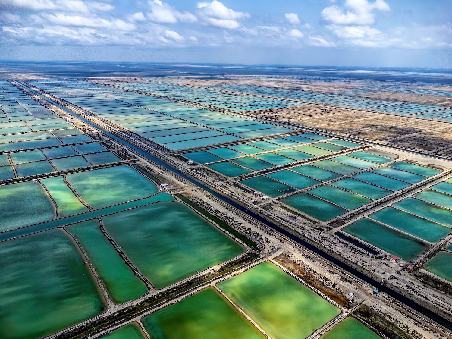 Bassins d’eau rectangulaires colorés vus du ciel, séparés par des routes en ligne droite.