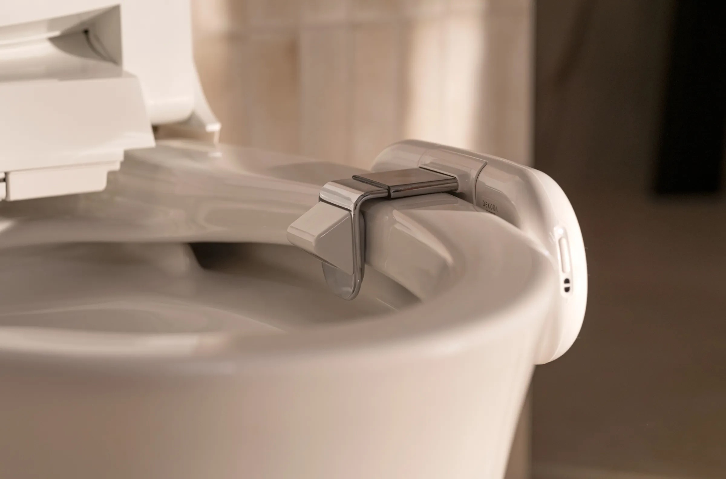 Buse de bidet fixée à une cuvette de toilettes, avec un jet d'eau en fonctionnement