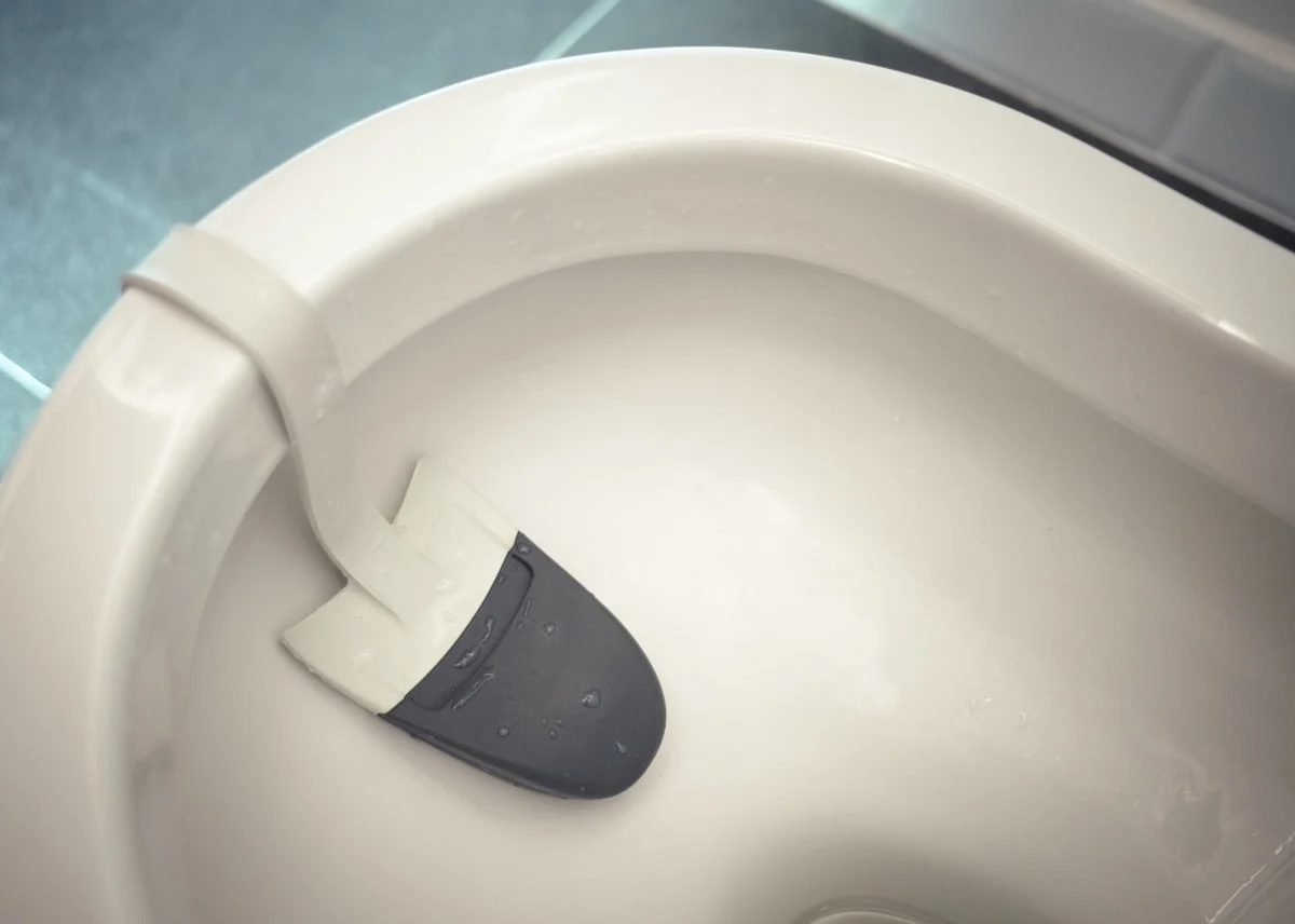 Intérieur d'une cuvette de toilettes avec un bloc désodorisant fixé sous le rebord.