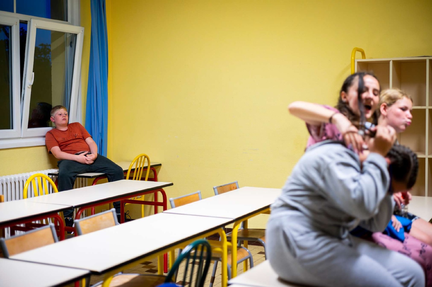 Des adolescents chahutent dans une salle de classe pendant qu’un autre reste assis à l’écart.