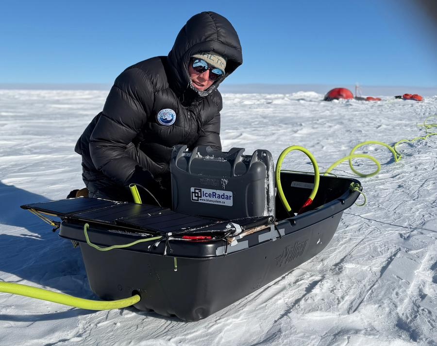 Scientifique en doudoune noire manipulant un appareil sur la neige en environnement polaire