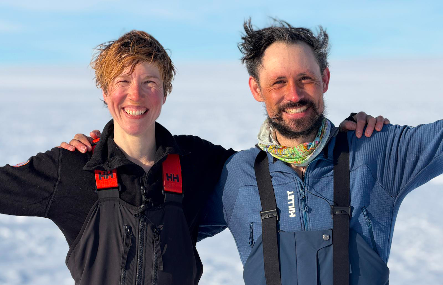 Deux personnes souriantes en tenue de froid posent ensemble dans un paysage enneigé.
