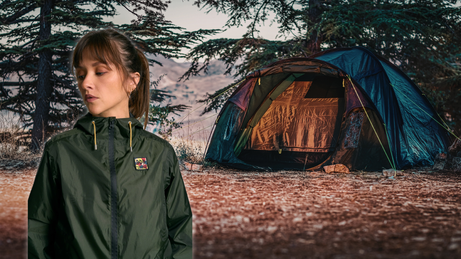 Femme en veste verte devant une tente de camping en forêt à l’automne