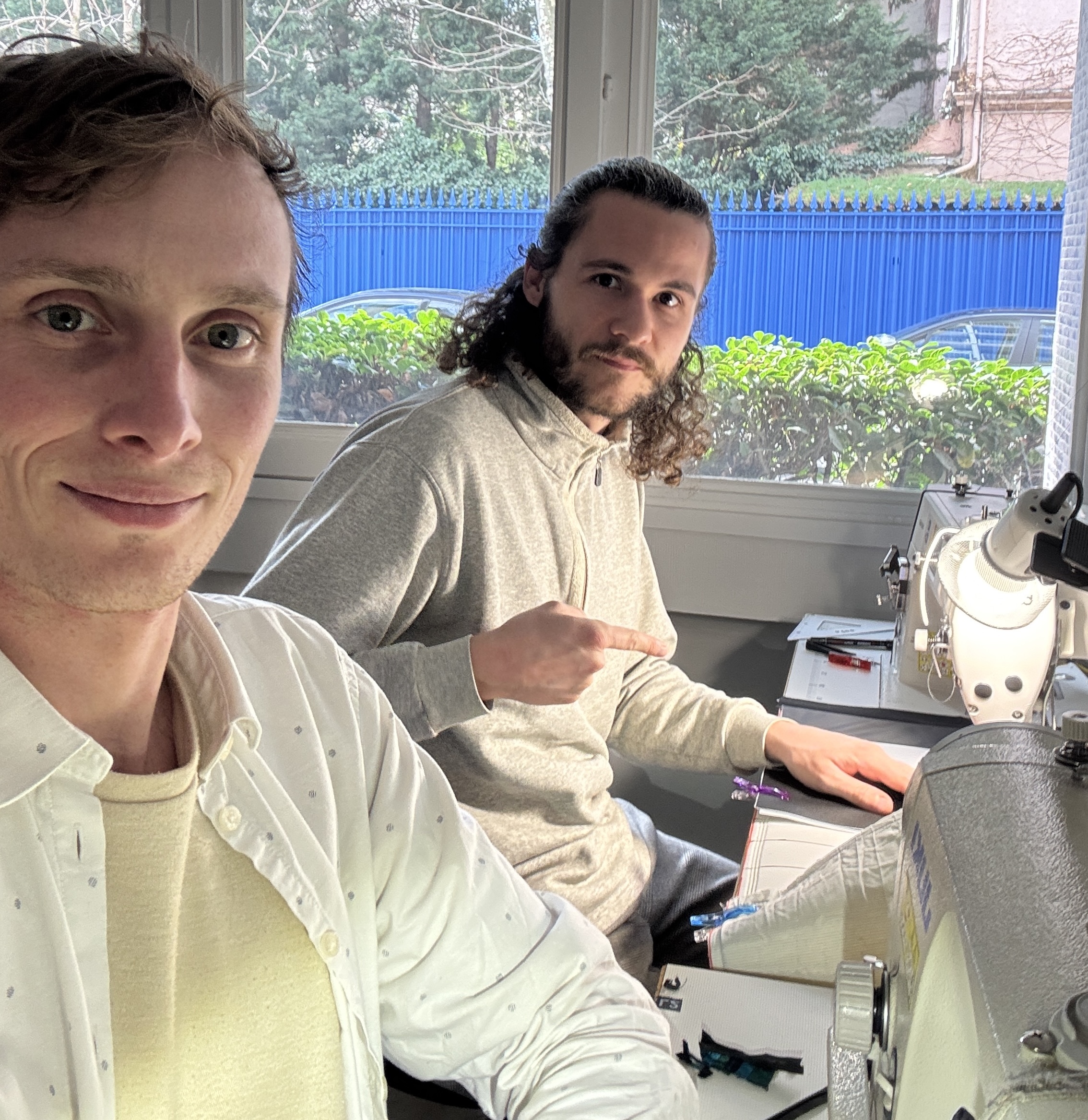Deux hommes assis à un bureau, l'un souriant, l'autre pointant vers un microscope.