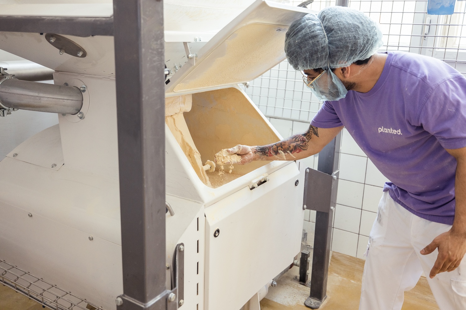 Un employé vérifie la pâte dans une machine de production en boulangerie industrielle.
