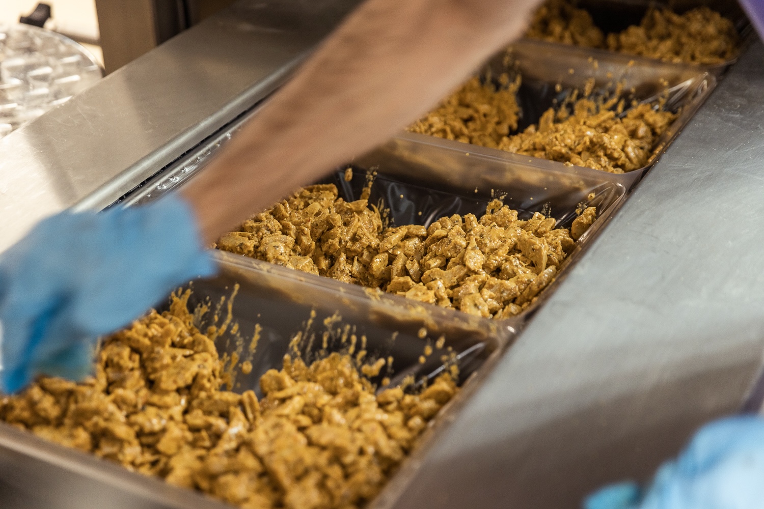 Préparation de pâte dans des moules industriels par un travailleur portant des gants bleus