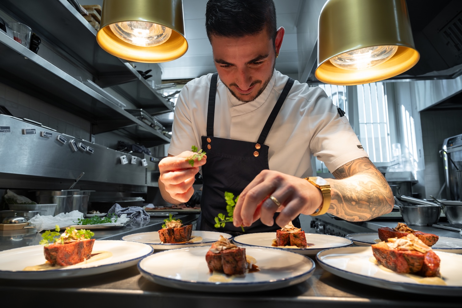 Un chef cuisine soigneusement des plats gastronomiques dans une cuisine professionnelle bien éclairée.