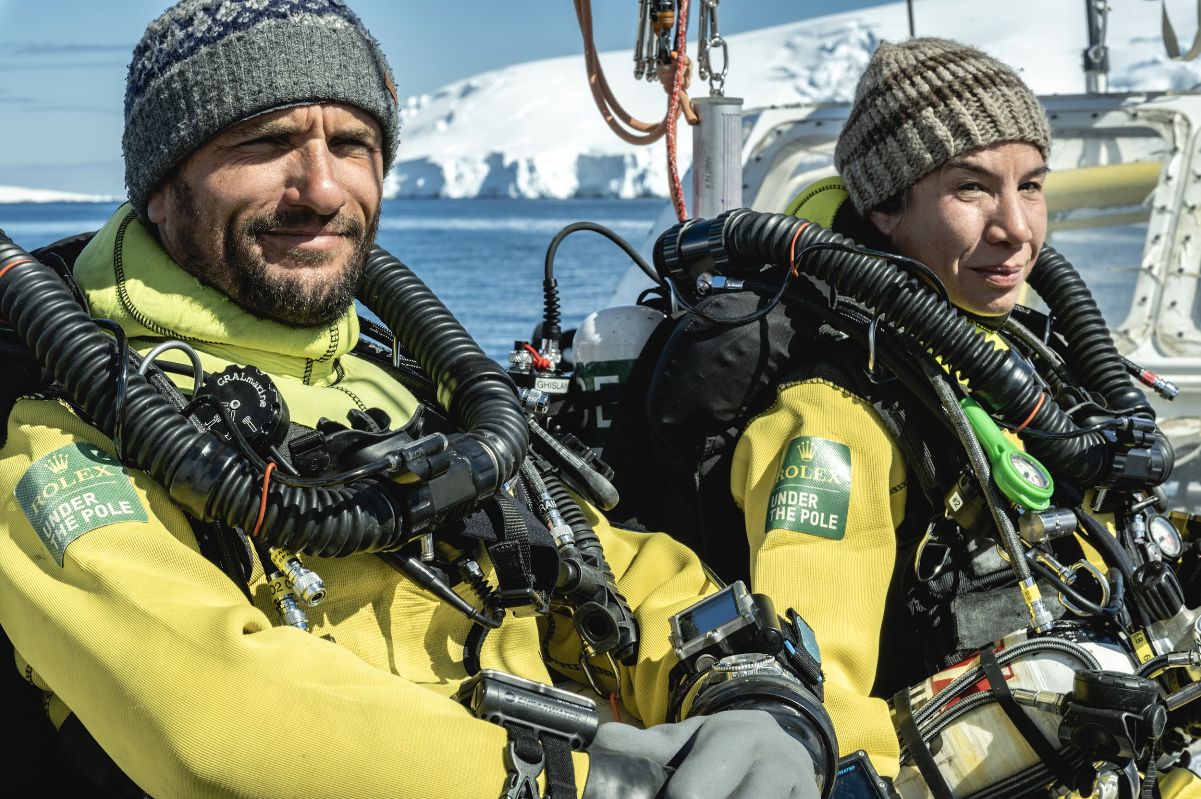 Deux plongeurs en combinaison jaune préparent une plongée en milieu polaire avec équipement technique.