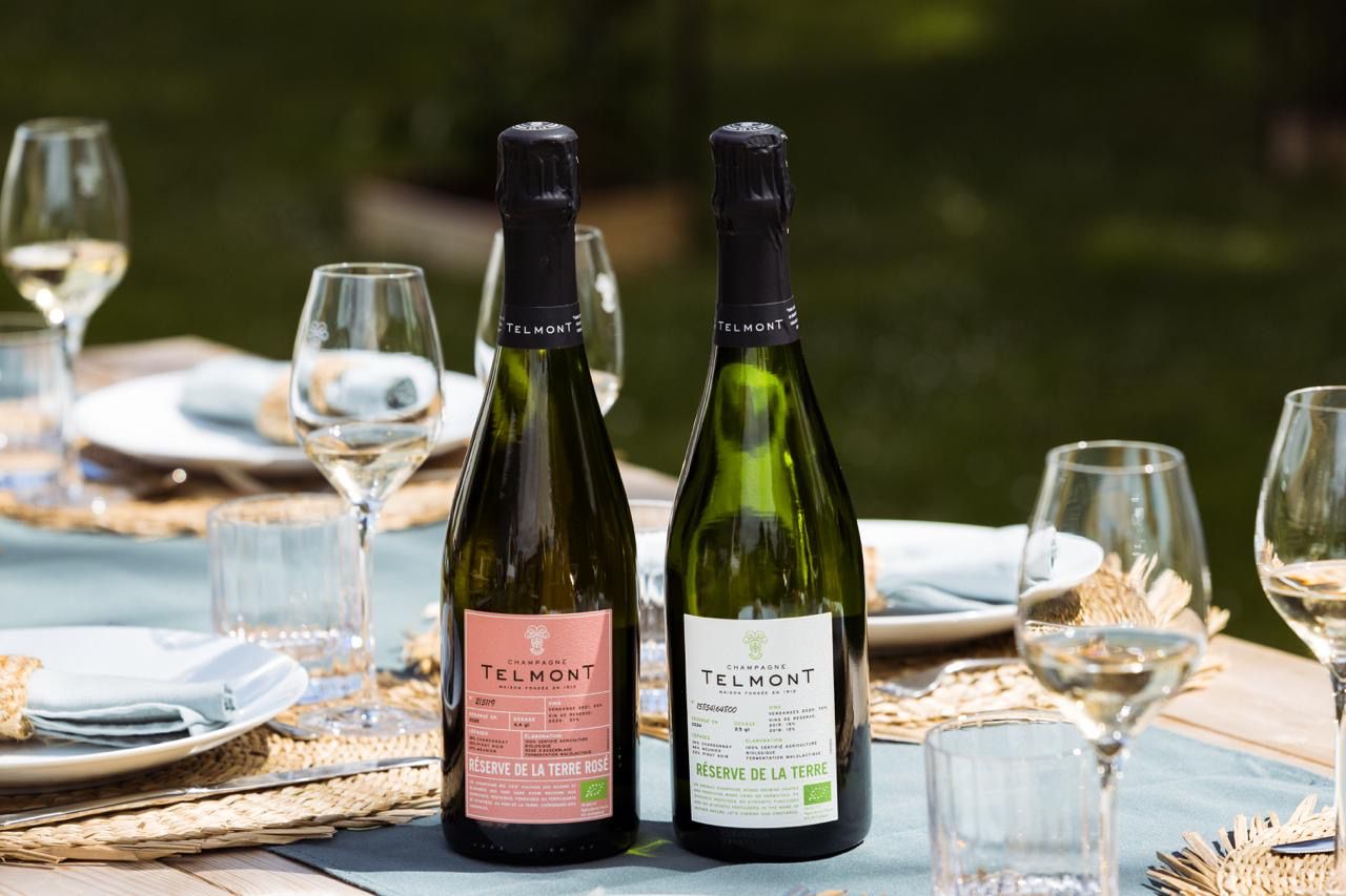Deux bouteilles de champagne Telmont sur une table dressée avec verres et assiettes.