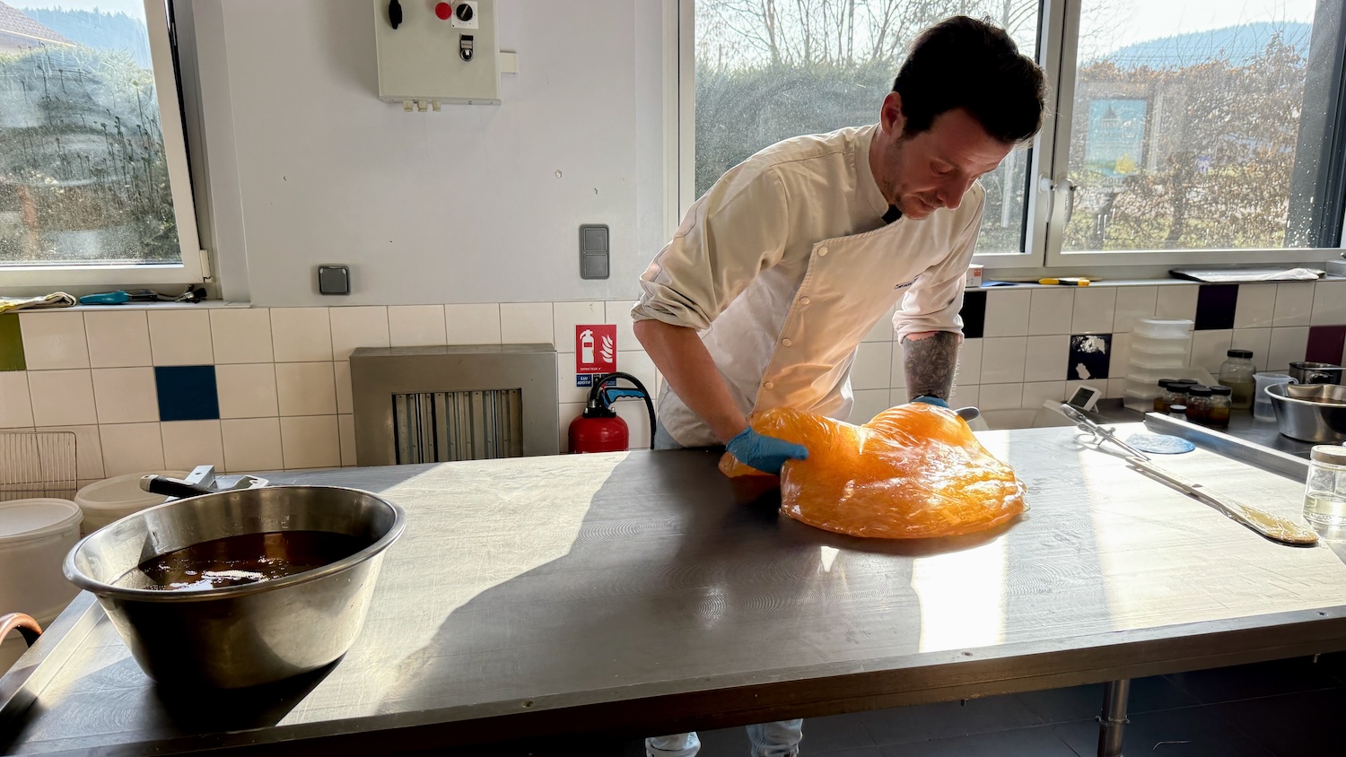 Chef préparant une grande masse de caramel sur une table en inox.