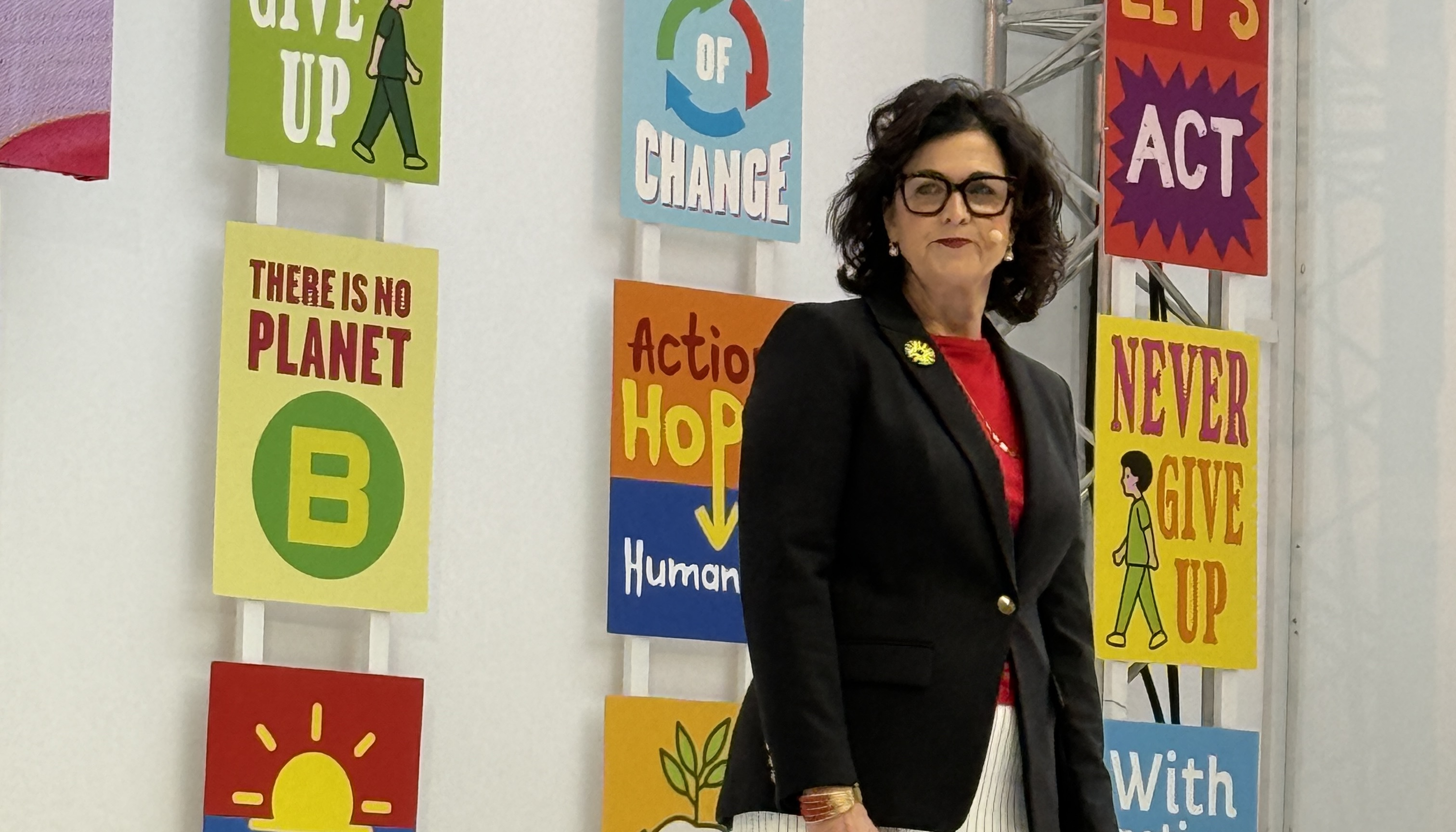 Femme debout devant des affiches colorées portant des messages écologiques et inspirants.