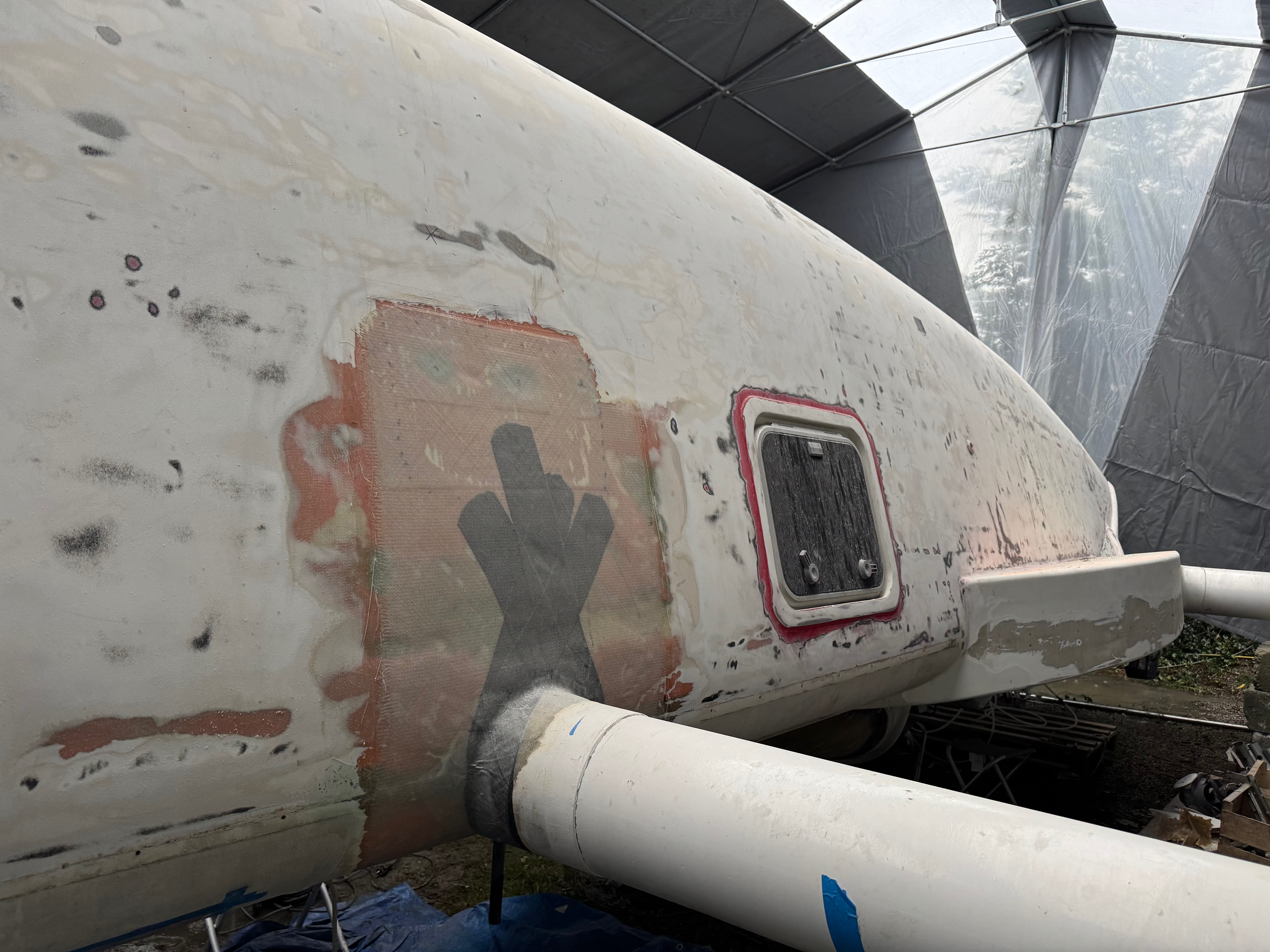 Vue rapprochée d'un avion en réparation avec une peinture écaillée et des patchs.