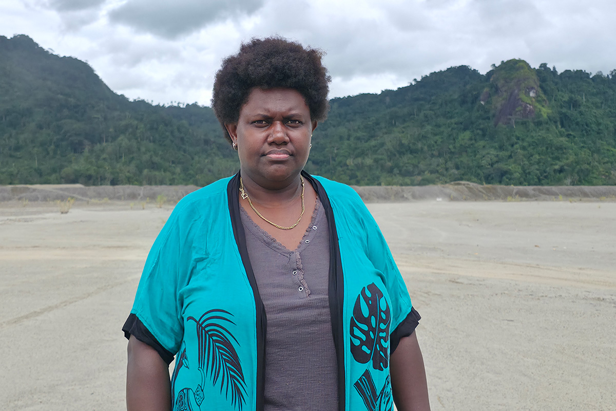 Une personne debout devant un paysage montagneux avec ciel nuageux.