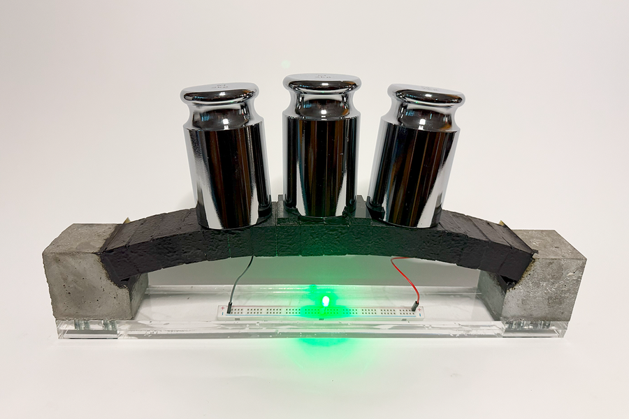 Poids métalliques sur une structure en équilibre, lumière verte en dessous.