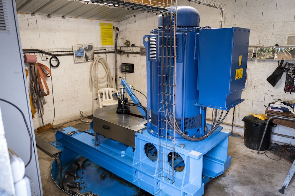 Machine industrielle bleue dans un atelier avec outils accrochés aux murs.