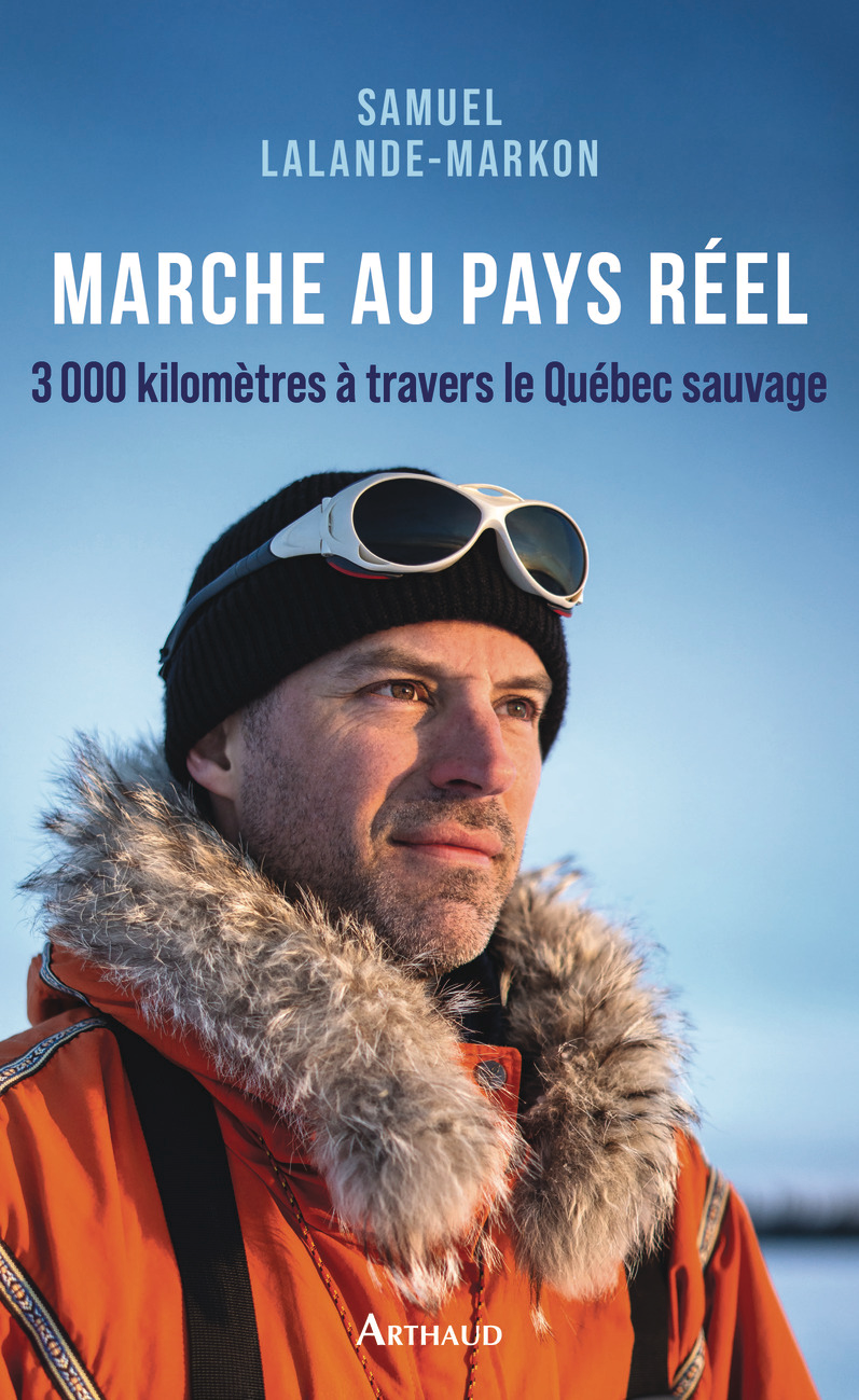 Homme en tenue d'hiver avec bonnet et lunettes, regardant vers l'horizon.