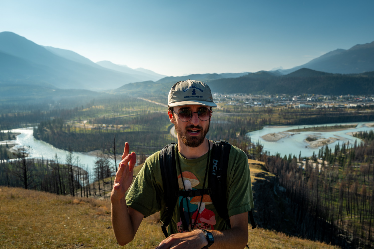 Homme en randonnée dans la nature avec rivière et montagnes en arrière-plan.
