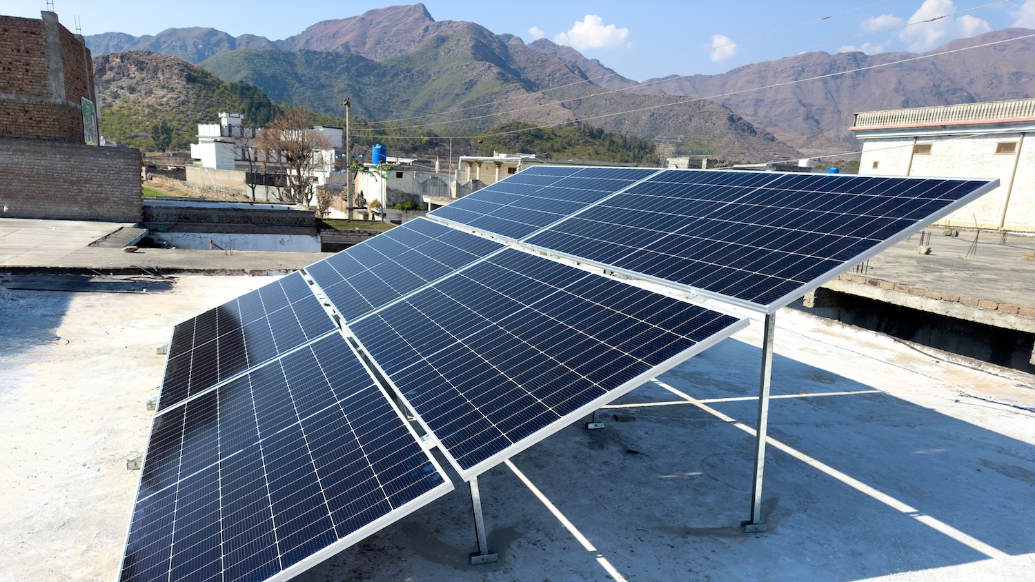 Panneaux solaires sur un toit avec des montagnes en arrière-plan sous un ciel bleu.