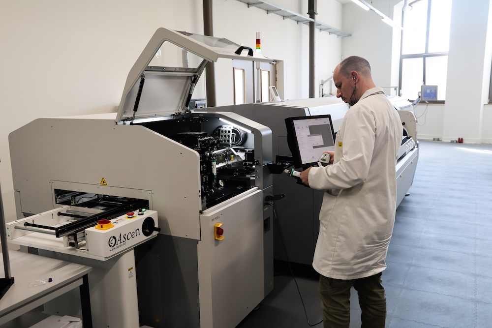 Technicien en blouse blanche utilisant une machine industrielle dans un atelier lumineux.